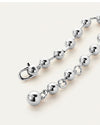A close-up view of a silver bracelet with spherical beads and a clasp engraved with the letters "JB", resting against a white background.