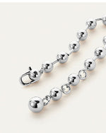 A close-up view of a silver bracelet with spherical beads and a clasp engraved with the letters "JB", resting against a white background.