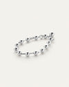 A silver bracelet with round beads evenly spaced around it, laid against a white background.