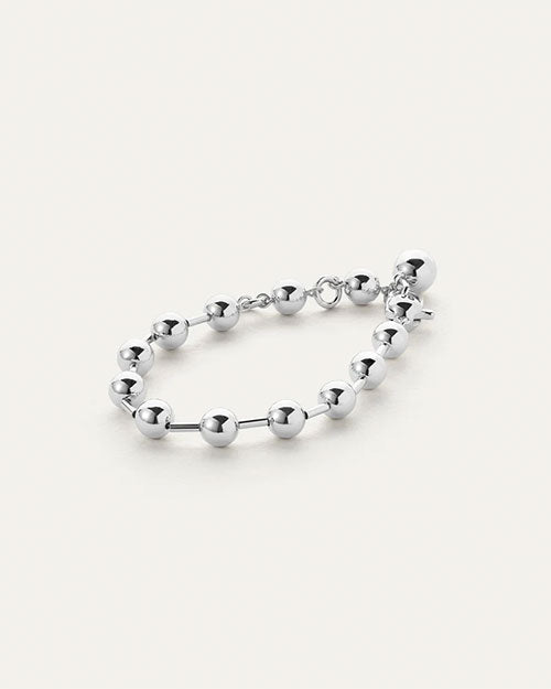 A silver bracelet with round beads evenly spaced around it, and a dangling sphere charm.