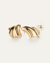 A pair of gold earrings laid against a white background with an abstract, fluid design which resembles a seashell. One of the ear backings is shown.