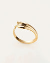 An overhead view of a gold cuff with an abstract, fluid design which resembles a seashell. The inside reads "JENNY BIRD"