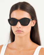 A model wearing stylish black sunglasses, showcasing a chic and modern look.