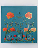 A blue-covered stationary box, "Good Juju Ink Enchanted Garden," embellished with floral designs.