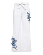 White pants with blue floral embroidery on a white background