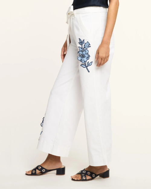 White pants with blue floral embroidery on a white background