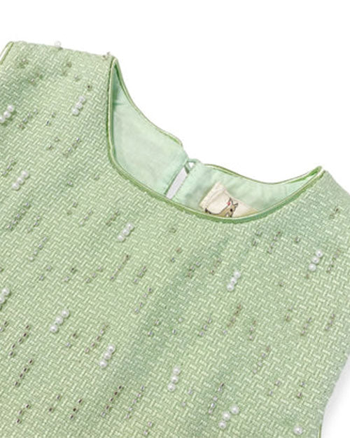 Up-close detail of a green tweed vest, embellished with beading and pearls on the front.