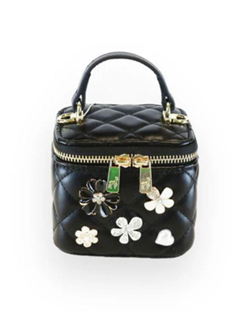Small black quilted vanity-style handbag with a top handle, gold-tone hardware, and decorative floral embellishments in black, white, and silver on the front.