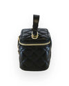 Side view of a small black quilted vanity-style handbag with a top handle, gold-tone hardware, and a plain diamond-stitched design without embellishments.