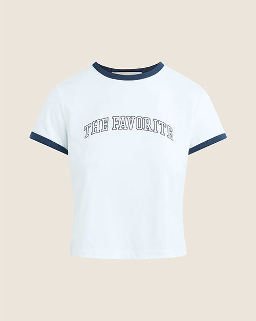 White short-sleeve ringer T-shirt with navy contrast trim at the crew neckline and sleeve cuffs. The graphic T-shirt features the text “THE FAVORITE” printed in an arched collegiate-style font across the chest.