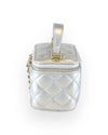 Side view of a small metallic silver quilted vanity-style handbag with a top handle, gold-tone hardware, and a plain diamond-stitched design without embellishments.