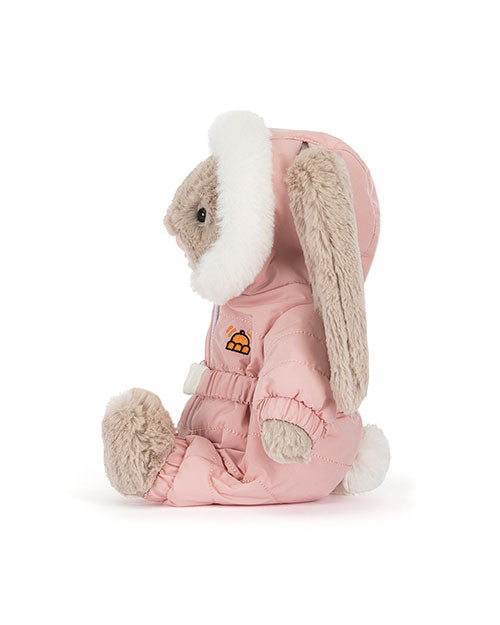 Side view of a plush rabbit toy dressed in a pink winter outfit with a white fur-lined hood, long floppy ears, and an embroidered orange and yellow igloo patch on the chest.