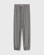 Brown-and-white patterned tapered pants with an elastic waistband, drawstring tie, and elastic cuffs at the ankles, shown against a light background.