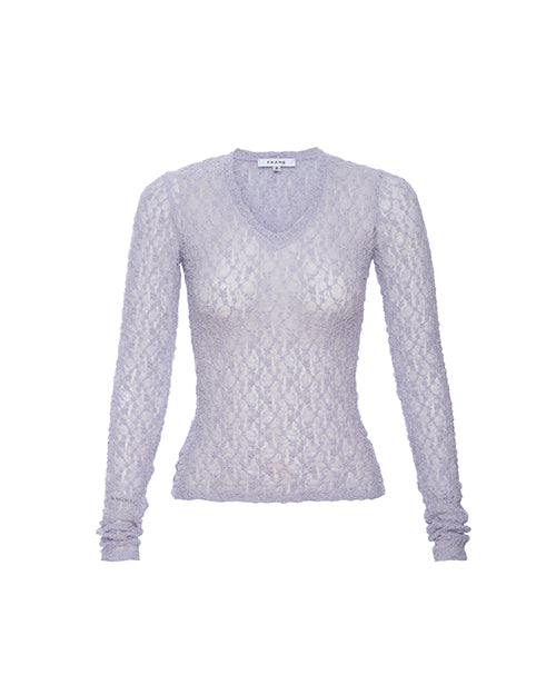 A long-sleeved, lilac-colored lace shirt with a V-neckline. The shirt has a delicate floral pattern throughout, and the fabric is mesh.