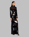 A long-sleeved, floor-length dress with horizontal panels of black and shiny sequins creating a striped pattern. The dress features a high neckline and is paired with black heeled sandals. 
