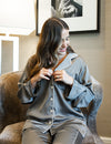 Model wearing pajama set seating on a sofa chair. Close up of pajama top.