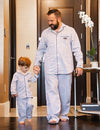 Dad and son standing and holing hands, both wearing Post Oak pajamas.