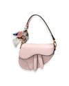 A pink saddle style purse adorned with a decorative bow, showcasing a stylish and playful design