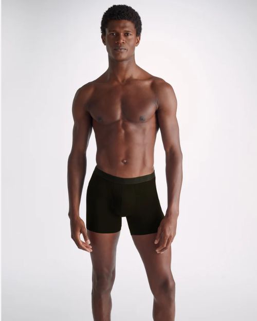 Image of a man standing wearing black long leg men's trunks.