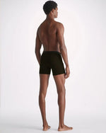 Image of a man standing backwards wearing black long leg men's trunks.