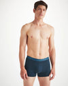 An image of a man from the knees up wearing navy blue boxer briefs with nautical knots print along the waistband