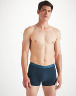 An image of a man from the knees up wearing navy blue boxer briefs with nautical knots print along the waistband