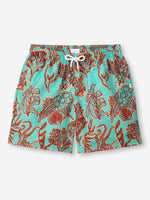 The turquoise men's swim shorts have dark red shadowed with neon orange drawings of an array of seaweed, kelp, and octopuses' legs.  The top of the swim shorts has an elastic waistband with a drawstring tie. 