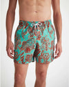 An image of a man standing from the below the knees to his chest wearing swim shorts.  The turquoise men's swim shorts have dark red shadowed with neon orange drawings of an array of seaweed, kelp, and octopuses' legs.  The top of the swim shorts has an elastic waistband with a drawstring tie. 
