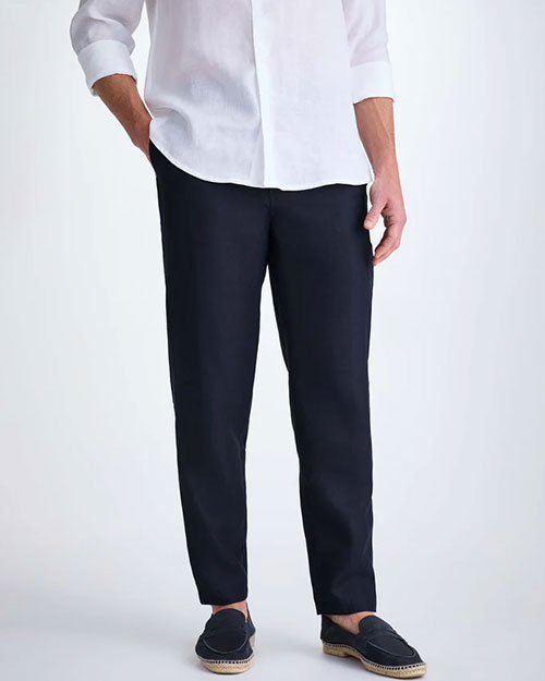  A man in a white shirt and navy pants stands confidently, showcasing a smart-casual style.