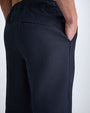 Back view of a man wearing navy pants, showcasing the fabric and fit against a neutral background.