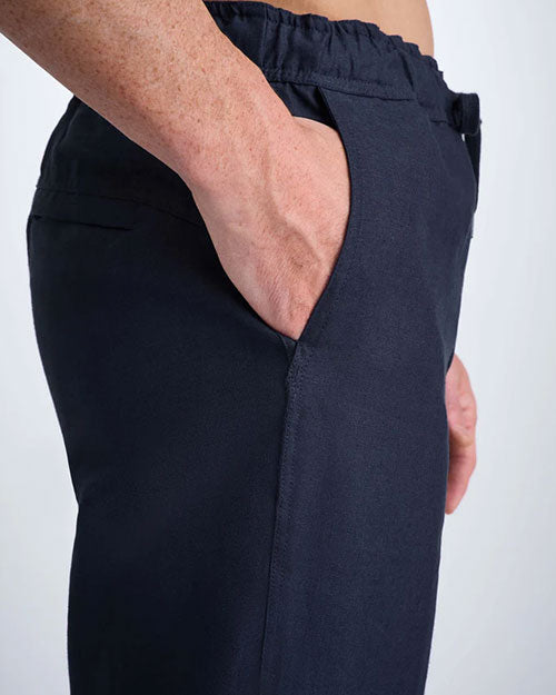 Side view of a man in navy pants, emphasizing the casual look and design of the clothing including the slanted pockets.
