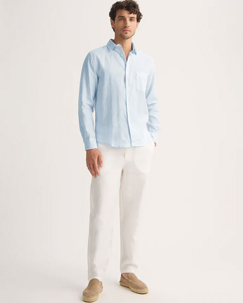 Model wearing a light blue and white striped linen long sleeve shirt with white pants.