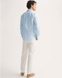 Model wearing a light blue and white striped linen long sleeve shirt with white pants.