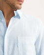 A man dressed in a long sleeve light blue shirt with white stripes, made of pure linen.