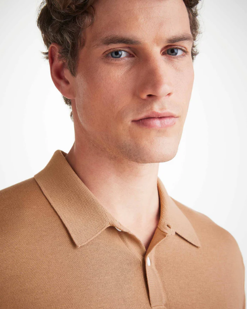 An image of a man from his shoulders to the top of his hair line showing off the camel color short sleeve polo shirt with a ribbed collar and two mother of pearl buttons 