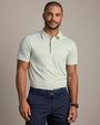 Person wearing a light green striped performance polo shirt with short sleeves, a zip placket, and navy pants in a studio setting.