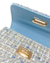 Up close image of a little girls blue tweed purse showing the detail of the gold clasp, inside flap which is solid light blue color, and the gold chain.

