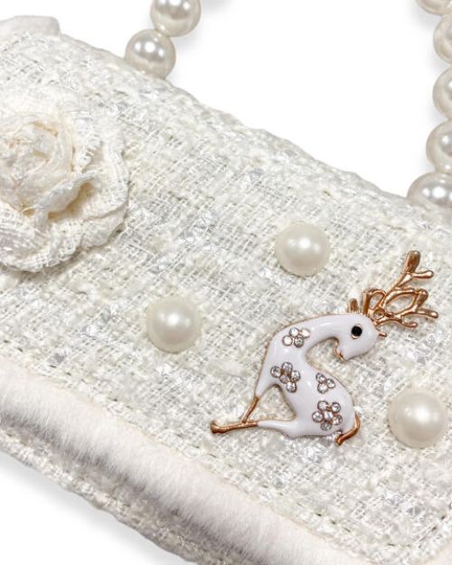 Up-close image of a girl's ivory tweed purse showing the detail of the fur on the edge, tweed ivory flower, 2 large pearls around the gold and ivory deer charm, and the large pearl handle. 