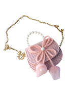 Little girls pink tweed pearl handle purse and gold chain with a large pink thin string bow on the front with a pearl in the middle of the bow.