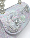 Up close image of a little girls purple tweed purse showing the detail of the tweed flower with pearl in the middle and heart pearl charm
