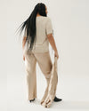A back view of high-waisted, light beige silk pants with a relaxed fit, draping gently over the legs. Pants are paired with matching top.