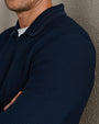 Close-up of a navy blue textured knit long-sleeve polo shirt highlighting the waffle-knit fabric, classic collar, and premium construction.