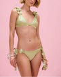 Sage green bikini set featuring a triangle bikini top with floral appliqué straps and matching side-tie bikini bottoms adorned with dimensional flower details on a pink studio background.