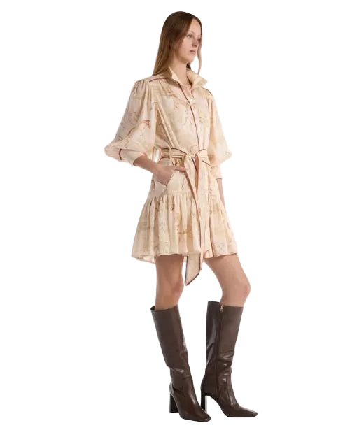 A side view of a woman wearing a short beige dress with a subtle horse print pattern and pockets. 