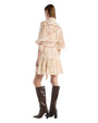The back view of a woman wearing a short beige dress with a subtle horse print pattern and brown knee-high boots. 