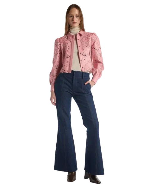  The woman is dressed in a pink jacket and blue jeans, presenting a trendy and relaxed look.