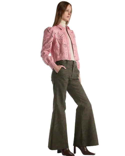 A woman is dressed in a pink jacket and pants, presenting a fashionable and colorful ensemble.