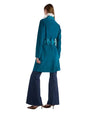 The back view of a woman in a luxurious blue coat and wide pants, highlighting a tailored silhouette and rich jewel-toned hue.