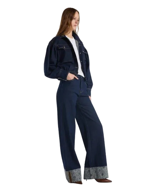 A woman in a denim jacket over a white shirt and jeans, exemplifying a stylish and relaxed ensemble.
