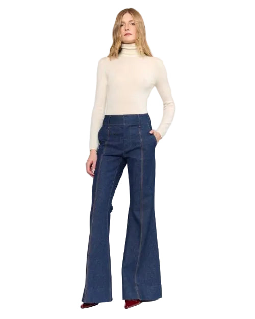 A woman is dressed in a turtleneck sweater and wide-leg denim pants, presenting a chic and relaxed fashion look.